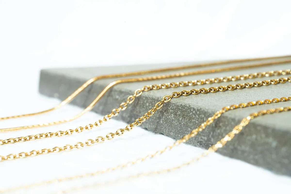 Fine gold chains on a grey stone slab