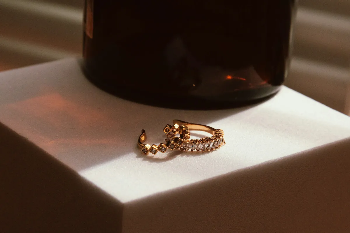 Gold huggie hoop earrings on a white block