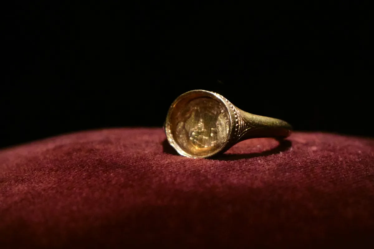 Gold signet ring on a red cushion