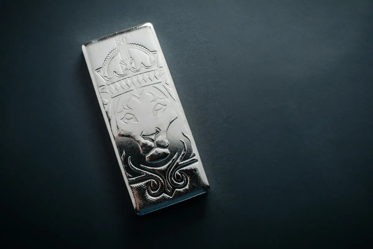 Fine-silver bar with a lion relief on a dark surface