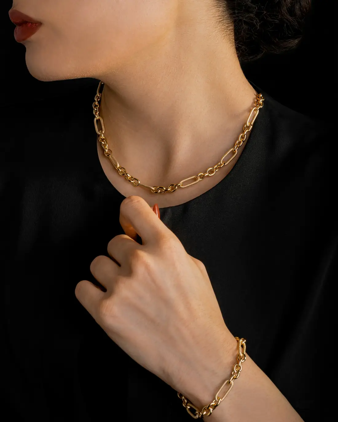 A gold link necklace worn against a black top